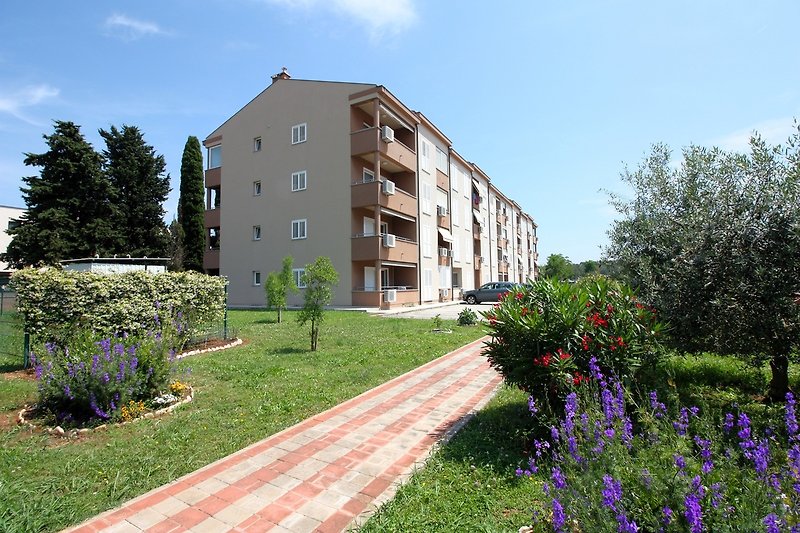 Schöner Garten mit Blumen und Bäumen, moderne Fassade, ruhige Umgebung.