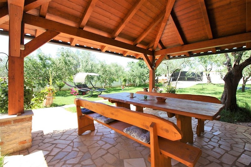 Terrasse couverte dans un beau jardin avec une grande table à manger