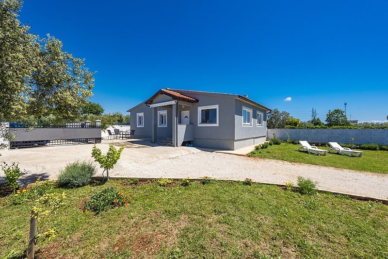 Gemütliches Landhaus mit Garten, Bäumen und Blick auf die Küste.