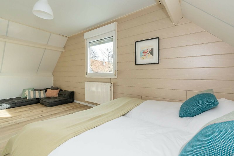 Schlafzimmer 1 mit Doppelbett, Kleiderschrank, Sitzecke und Smart TV.