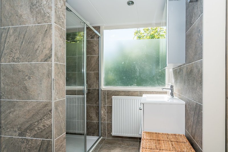 Das moderne, neue Badezimmer mit Regendusche und Waschbecken