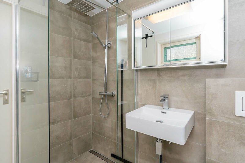 Das neue, moderne Badezimmer mit Regendusche, Waschbecken und Toilette