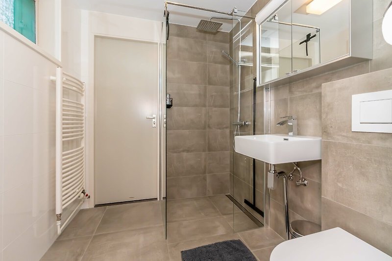 Das neue, moderne Badezimmer mit Regendusche, Waschbecken und Toilette