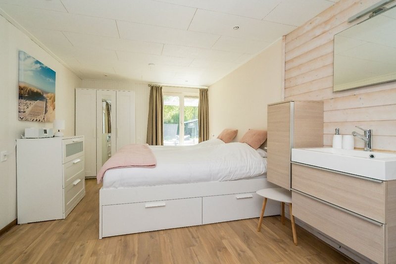 Slaapkamer 1 met tweepersoonsbed, badkamermeubel en kledingkast
