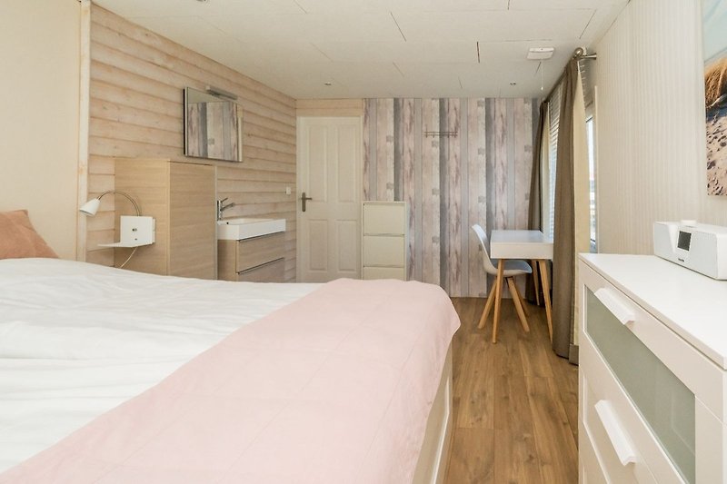 Slaapkamer 1 met tweepersoonsbed, badkamermeubel en kledingkast
