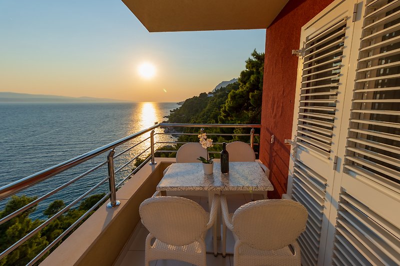 Ein sonniger Balkon mit Blick auf das Meer und einem bequemen Stuhl.