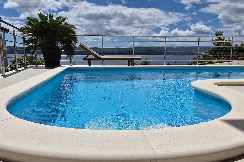 Tropische Oase mit Pool, Palmen und Sonnenliegen.