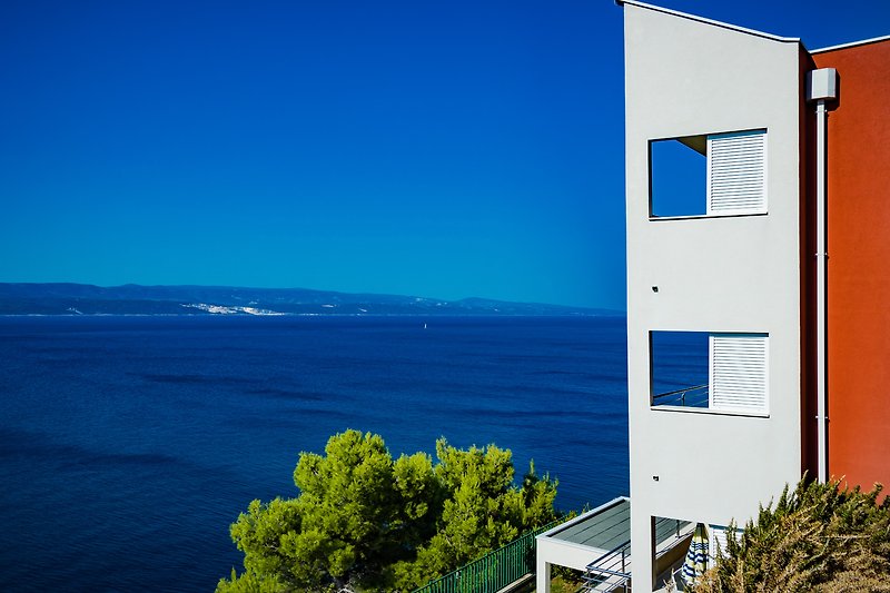 Moderne Wohnung mit Meerblick, Balkon und grüner Umgebung.
