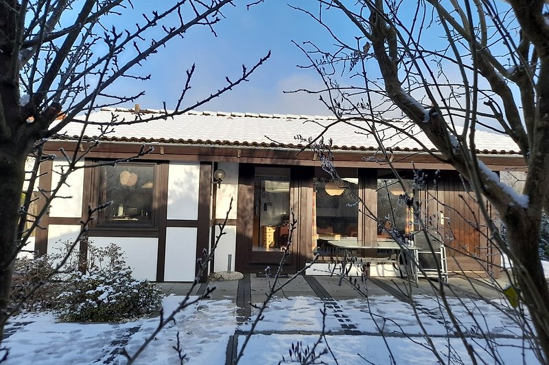 Ein charmantes Haus in einer verschneiten Landschaft mit winterlichem Flair.