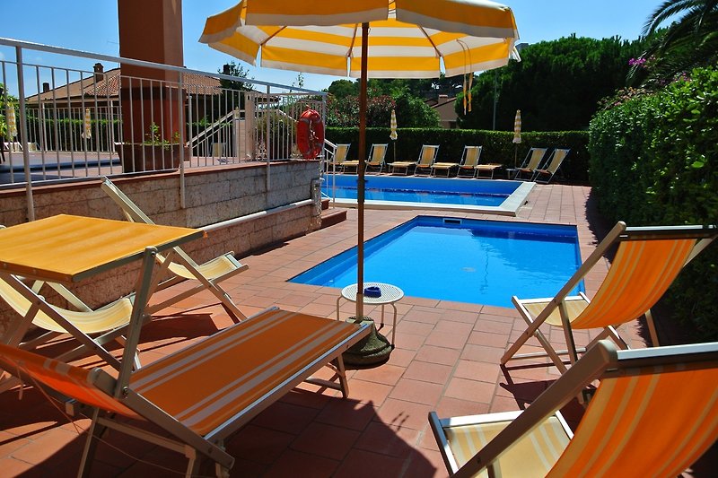 Una lussuosa piscina con mobili da esterno e ombrelloni.