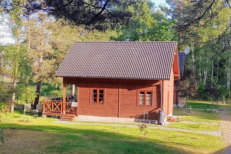 Blockhütte mit großem Garten, Holzschuppen und überdachter Veranda.