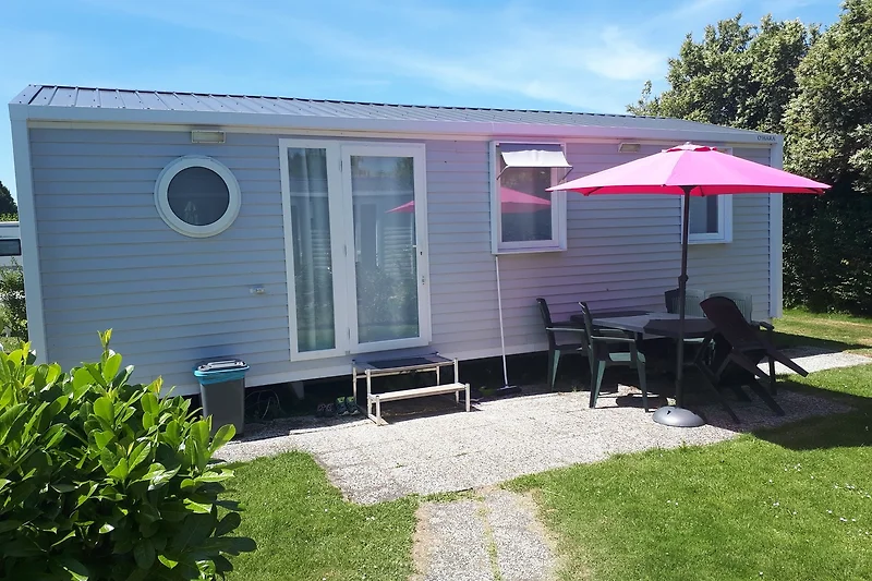 Mobilheim mit schattiger Terrasse, Gartenmöbeln und blühenden Geranien