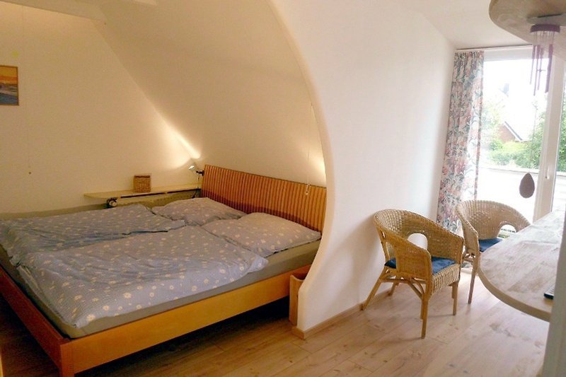 Gemütliches Bett im Obergescoss; dieses Zimmer hat auch Balkonzugang