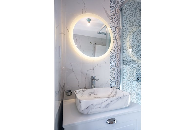 Prekrasna kupaonica s bijelim umivaonikom, ogledalom i slavinom.