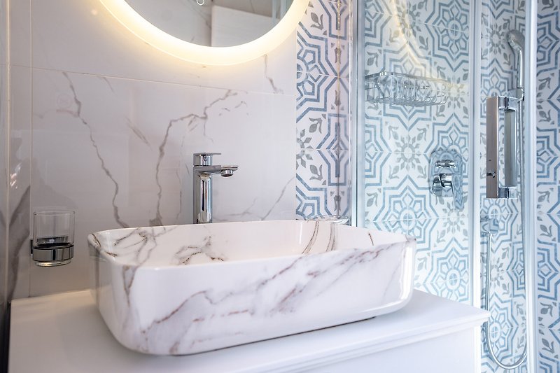 Prekrasna kupaonica s bijelom kadom, keramičkim umivaonikom i ogledalom.