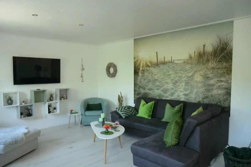 Wohnbereich mit Sofa, Sessel, TV, Kunst und stilvollen Details.