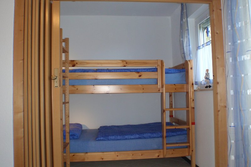 Gemütliches Schlafzimmer mit Etagenbett und Holzmöbeln.