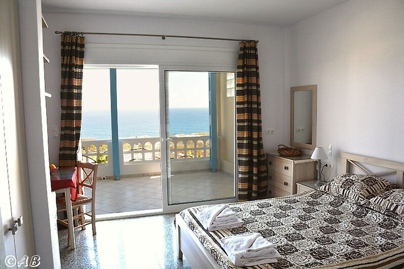Gemütliches Schlafzimmer mit Holzbett und Fenster mit Vorhängen.
