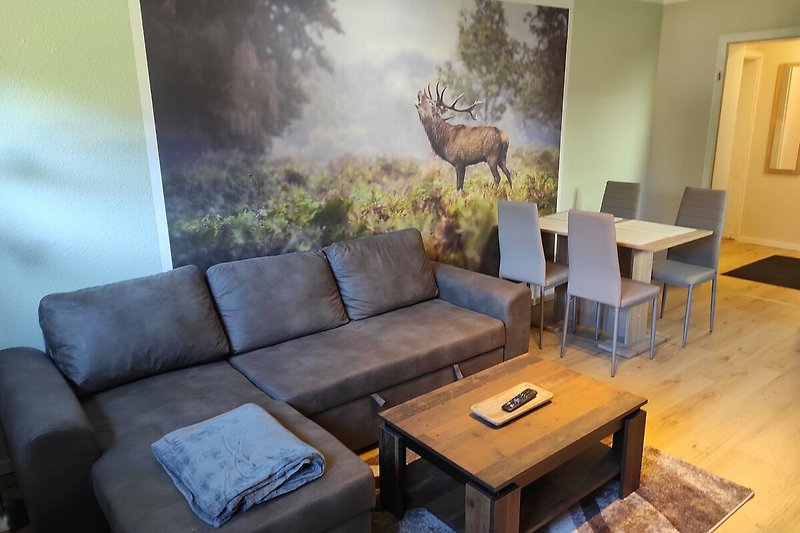 Gemütliches Wohnzimmer mit bequemer Couch, stilvollem Mobiliar und Kunst an der Wand.