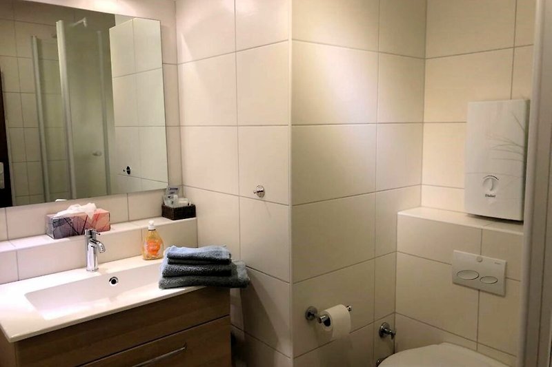 Schönes Badezimmer mit Holzspiegel und modernem Waschbecken.