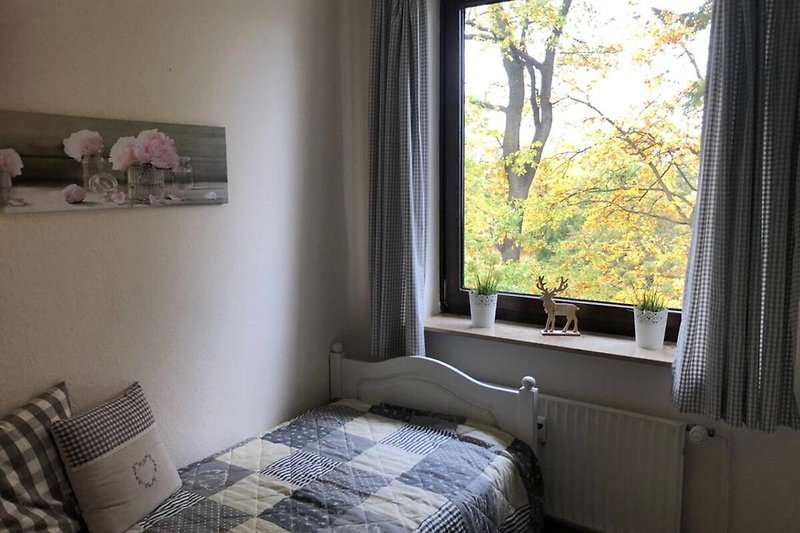 Gemütliches Schlafzimmer mit Holzbett, Vorhängen und Pflanzen.