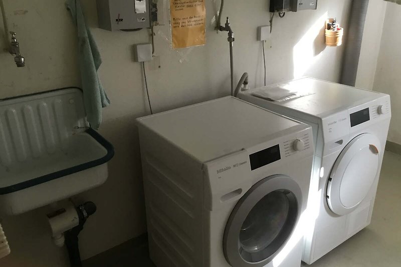 Moderne Waschküche mit Waschmaschine, Trockner und allen notwendigen Utensilien.
