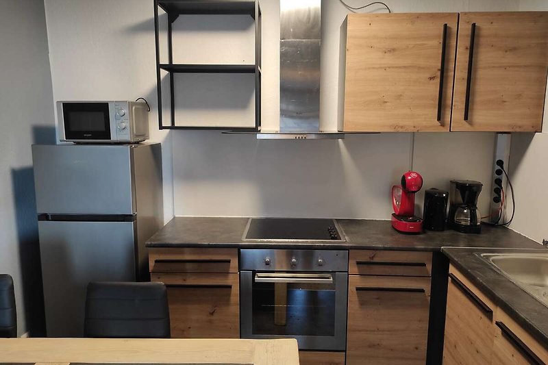 Moderne Küche mit Holzschrank, Arbeitsplatte, Spüle und Elektrogeräten.