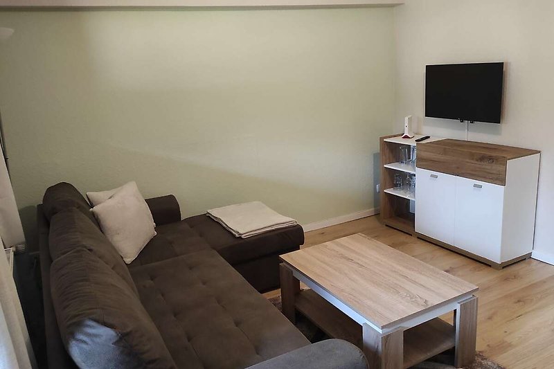 Gemütliches Wohnzimmer mit bequemer Couch, Holzmöbeln und moderner Einrichtung.