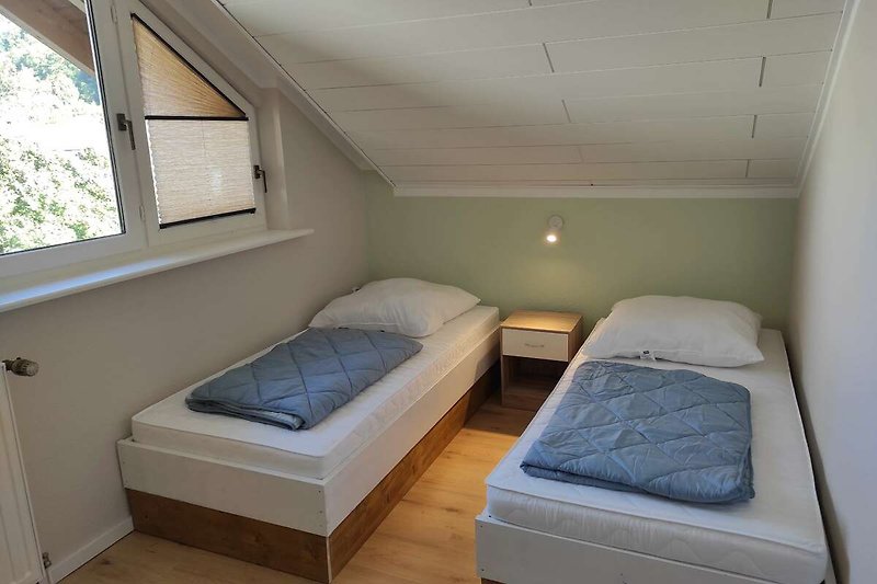 Gemütliches Schlafzimmer mit Holzboden und großem Fenster.