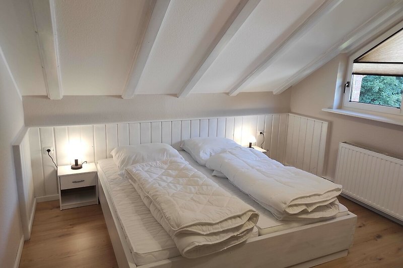 Gemütliches Schlafzimmer mit Holzbett, Textilien und Lampen.