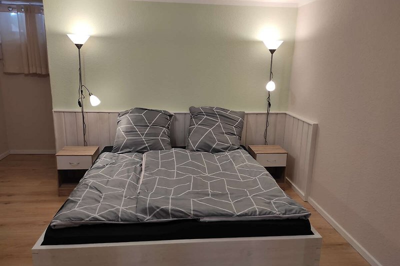 Modernes Schlafzimmer mit gemütlichem Bett, stilvoller Beleuchtung und elegantem Interieur.