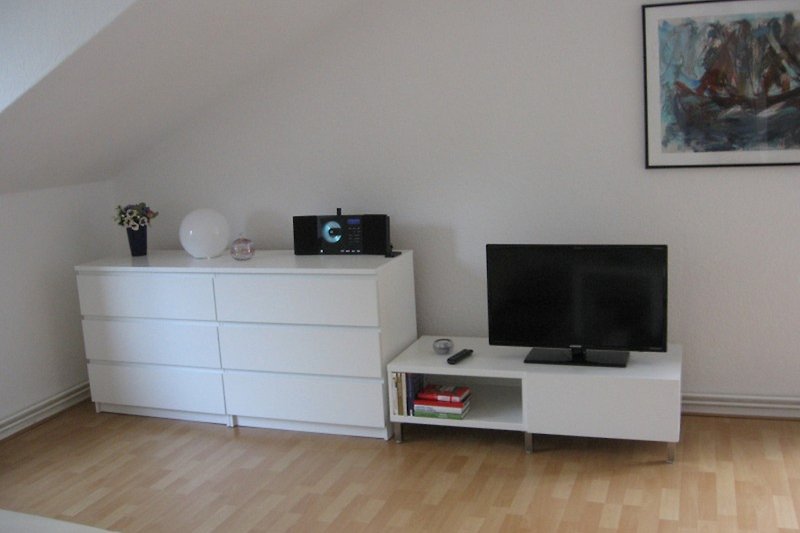 Moderne Inneneinrichtung mit grauer Wand, Holzmöbeln und Fernseher.