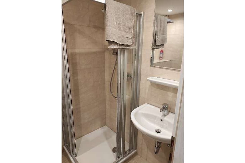 Modernes Badezimmer mit stilvoller Dusche, Spiegel und Waschbecken.