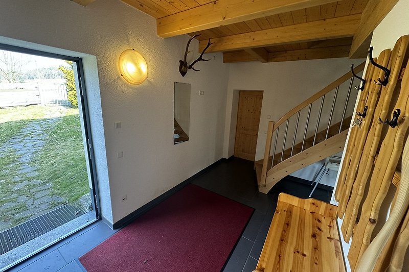 Geräumiges Wohnzimmer mit Holzinterieur, großen Fenstern und Deckenventilator.