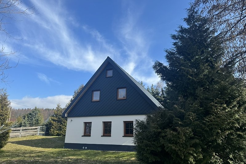 Rustikales Haus mit grünem Garten und blauem Himmel.
