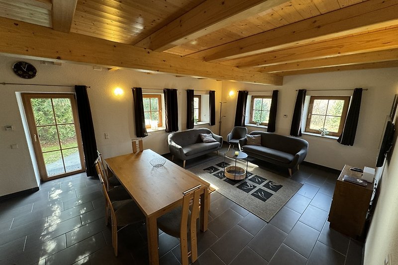 Stilvolles Wohnzimmer mit Holzmöbeln, gemütlicher Couch und Fenster.