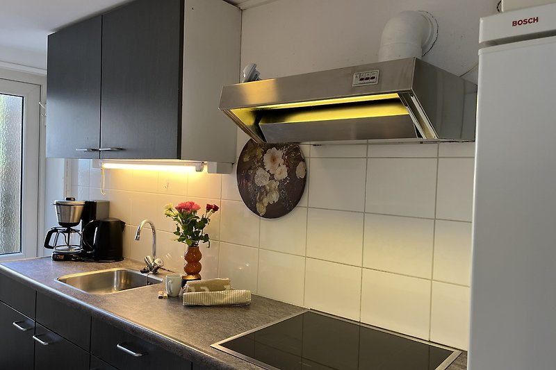 Gemütliche Küche mit Holzschränken, gelben Wänden und Pflanzen.