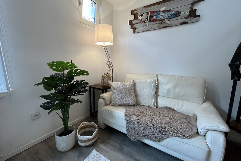 Gemütliches Wohnzimmer mit Pflanzen, Couch und Tisch.