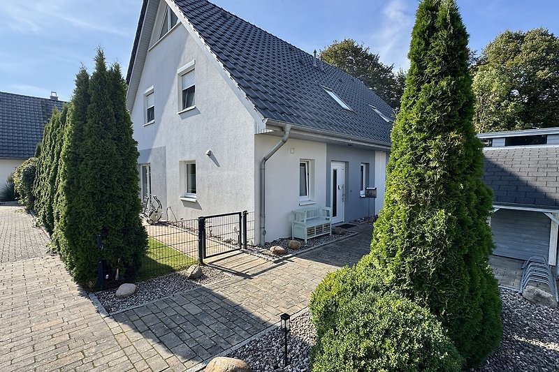 Gemütliches Haus mit Einfahrt und grüner Landschaftsgestaltung.