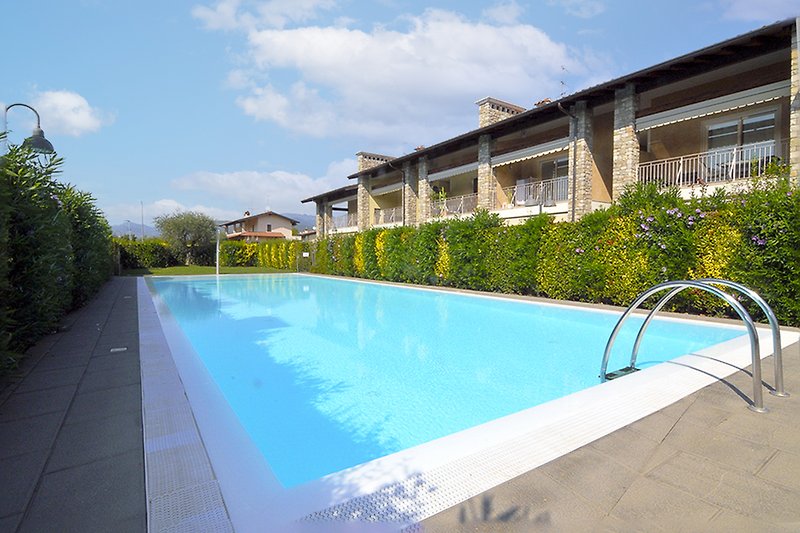 Una vista panoramica di una piscina  e un giardino ben curato.