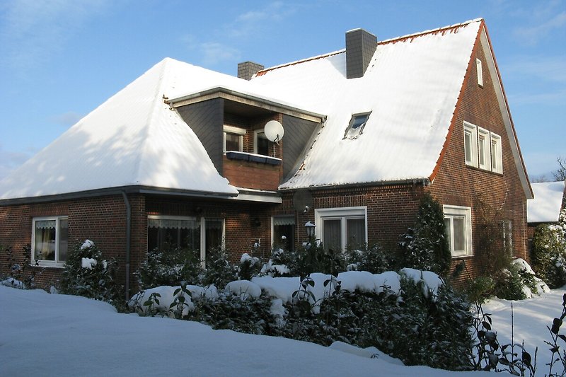 Winterliches Ferienhaus mit verschneitem Dach und gemütlichem Fensterblick.