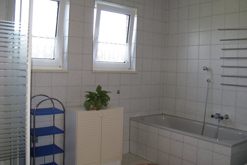 Gemütliches Badezimmer mit Badewanne, Fenster und Pflanzen.