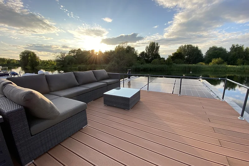 Großzügige Terrasse mit Holztisch, Sitzgruppe und Blick ins Grüne.