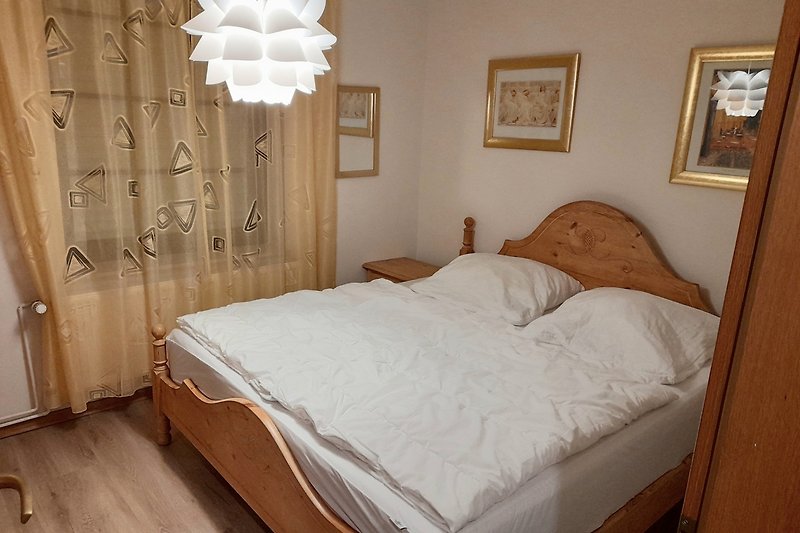 Schlafzimmer EG mit gemütlichem Bett, Lampen und Bilderrahmen.