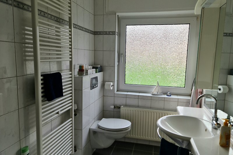 Ferienwohnung "Erika": Badezimmer mit Fenster, Badewanne, Dusche und Handtuchwärmer