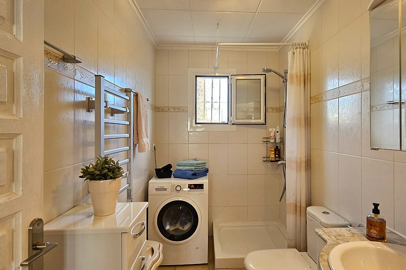 Badezimmer mit Dusche, Waschmaschine und Fenster