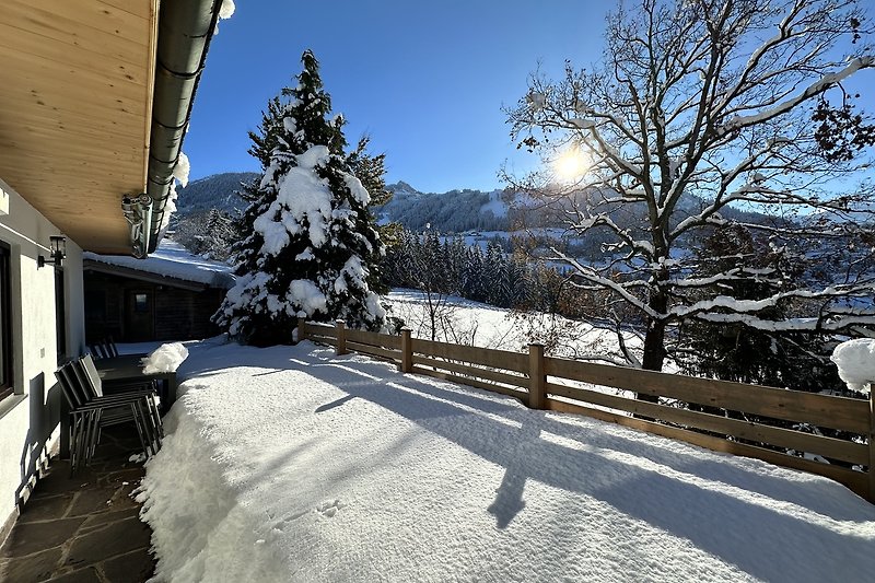 Winterliches Ferienhaus mit verschneiter Berglandschaft.