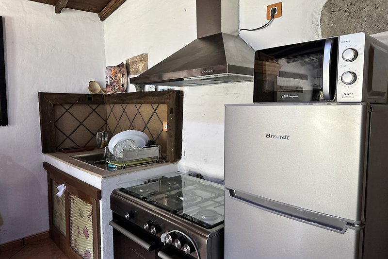 Moderne Küche mit grauen Schränken, Arbeitsplatte und Geräten.