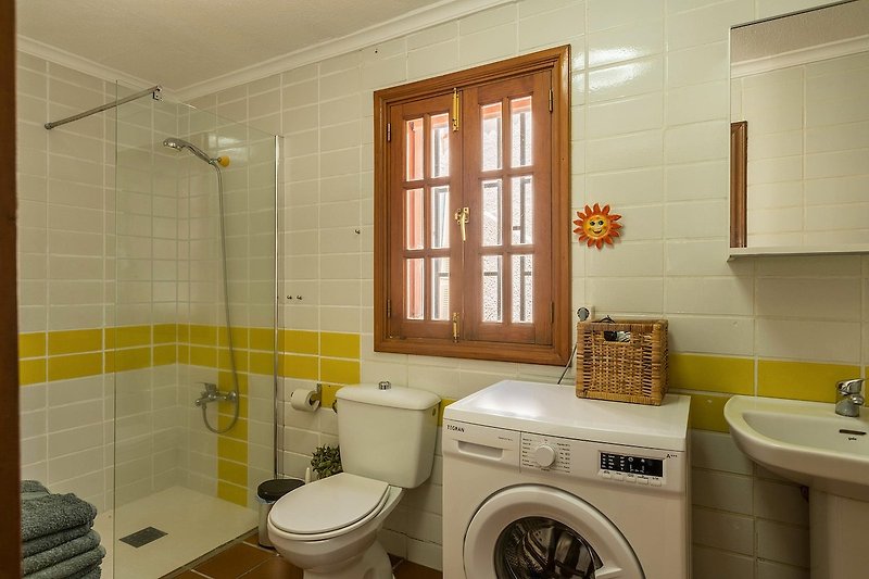 Hermoso baño con accesorios modernos y ventana con cortina.