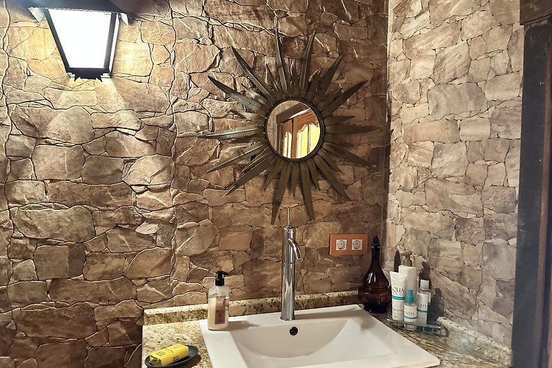 Badezimmer mit Spiegel, Waschbecken und Beleuchtung in Holzoptik.